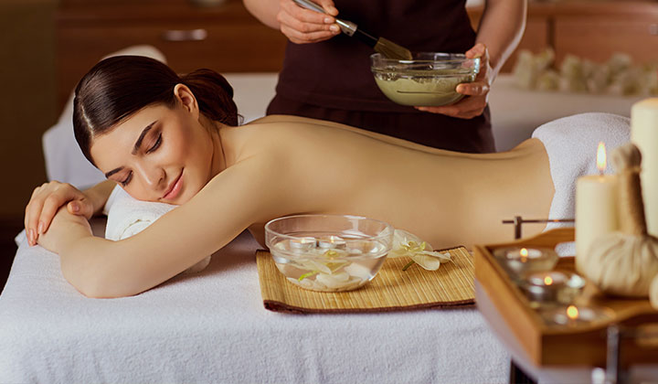 woman is put on a mask on her back in spa salon