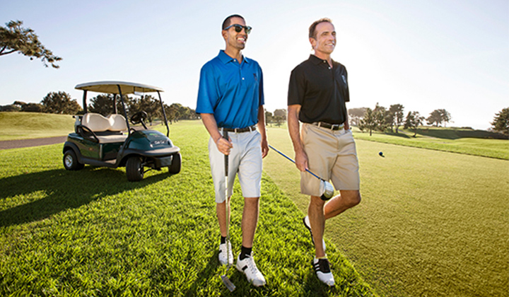 Two golfers walk across the green