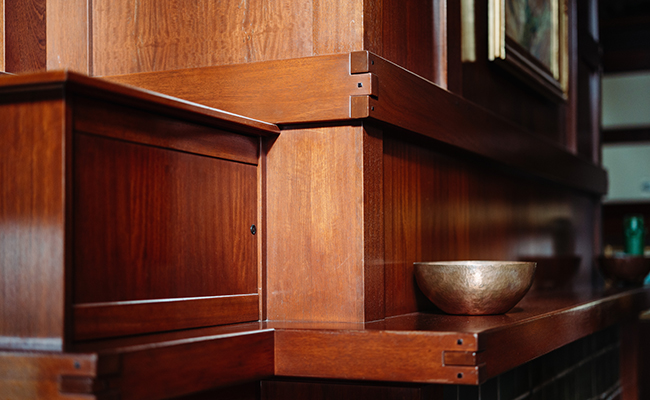 Detailed woodwork on a mantel at The Lodge at Torrey Pines, showcasing the exposed, interlocking joinery characteristic of the Greene brothers inspired by Japanese techniques like dougong.