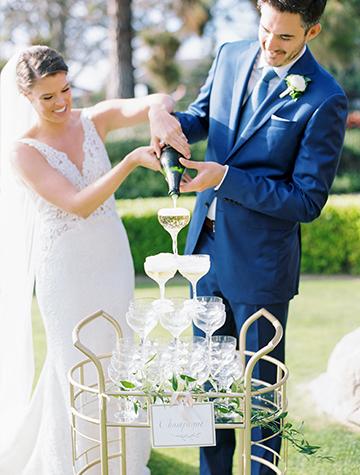 The newlyweds pouring champagne into a coupe tower for their first toast at their classic wedding at The Lodge at Torrey Pines